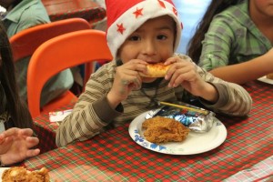 small boy wearing Santa hat, enjoying breakfast